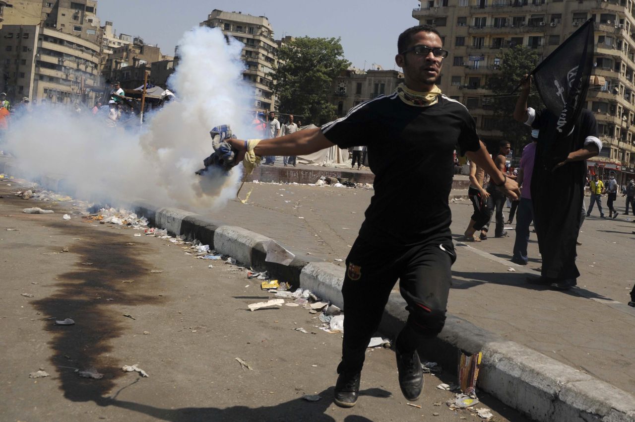 An Egyptian protester throws a tear gas canister toward riot police during clashes near the U.S. Embassy in Cairo on Friday.