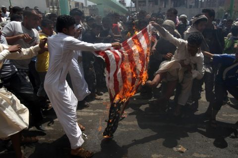 Yemeni protesters burn a U.S. flag on a street leading to the U.S. Embassy in Sanaa on Friday, September 14.