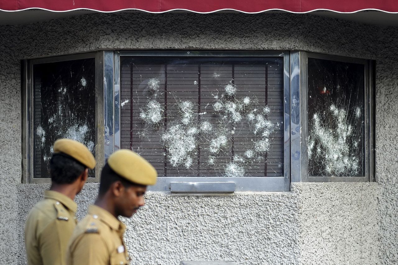 Indian policemen walk past smashed windows of the U.S. Consulate building, caused by a mob of demonstrators protesting against an anti-Islam film, in Chennai, India, on Friday, September 14.