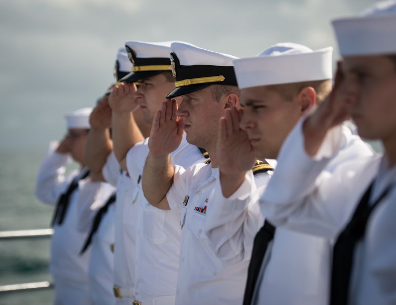Navy members salute in honor of Armstrong.