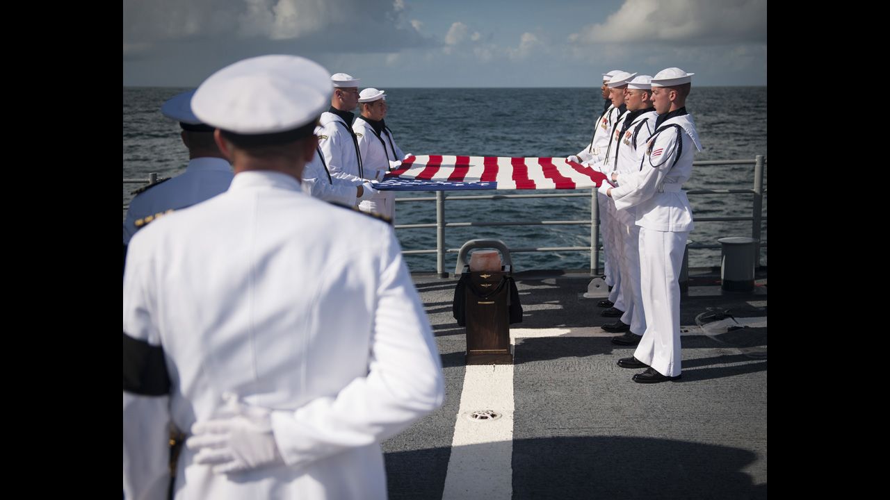 Members of the U.S. Navy ceremonial guard hold an American flag over the Armstrong's remains.  