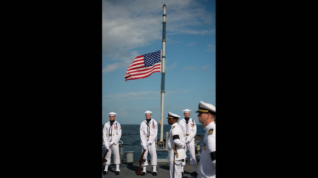The American flag on the ship is seen at half-mast.