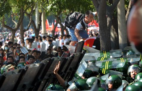 A protester tries to climb over a security barrier during an anti-Japanese protest outside its embassy in Beijing on September 15, 2012.