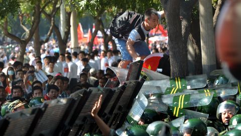 A protester (top) attempts to climb over a security barrier during an anti-Japanese protest outside the Japanese embassy in Beijing on September 15, 2012. 