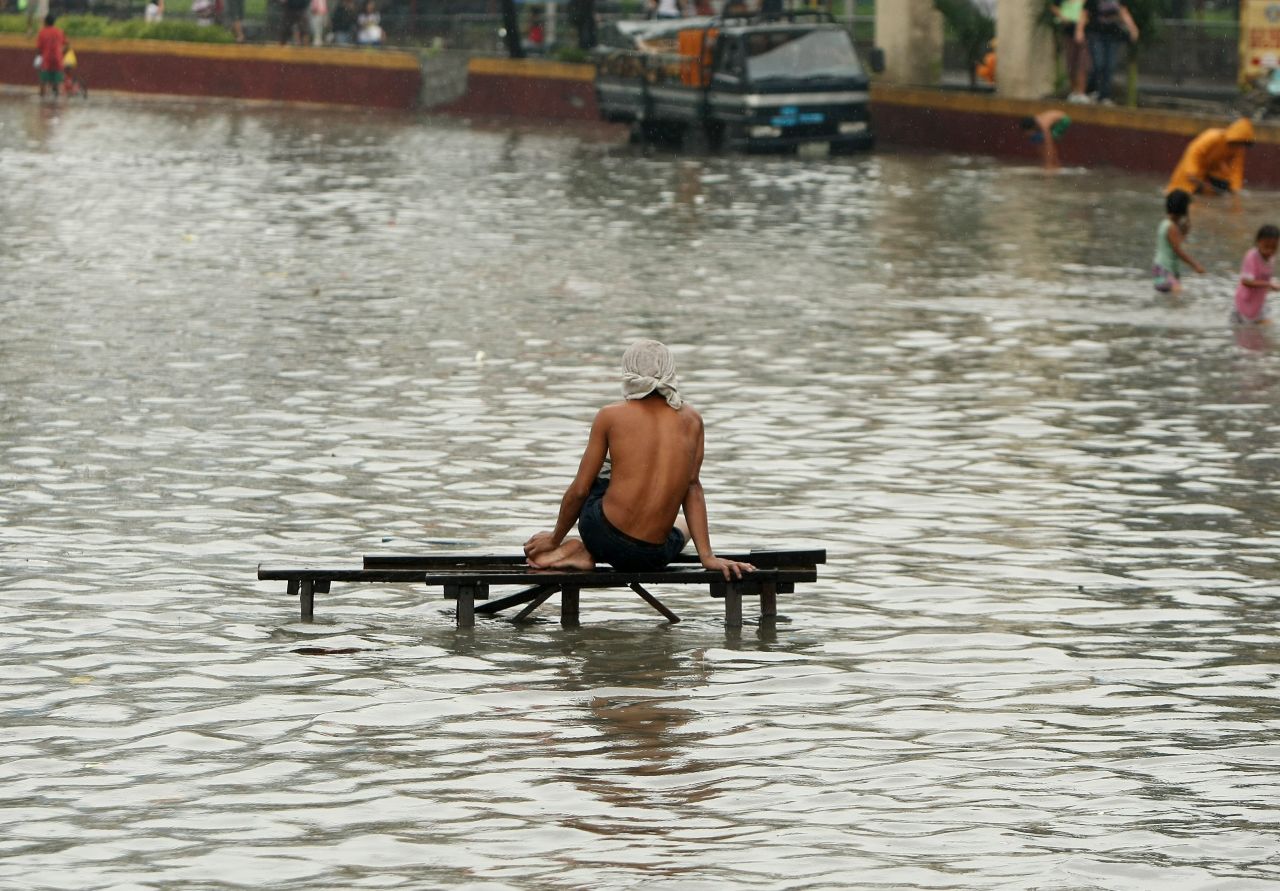  A resident rests on a flooded street in Paranaque.