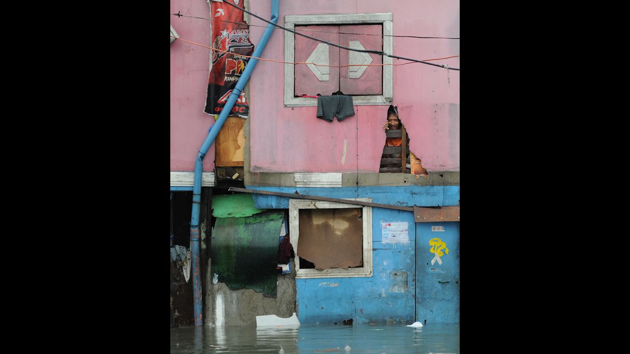A resident peers through his half-submerged house in Manila.