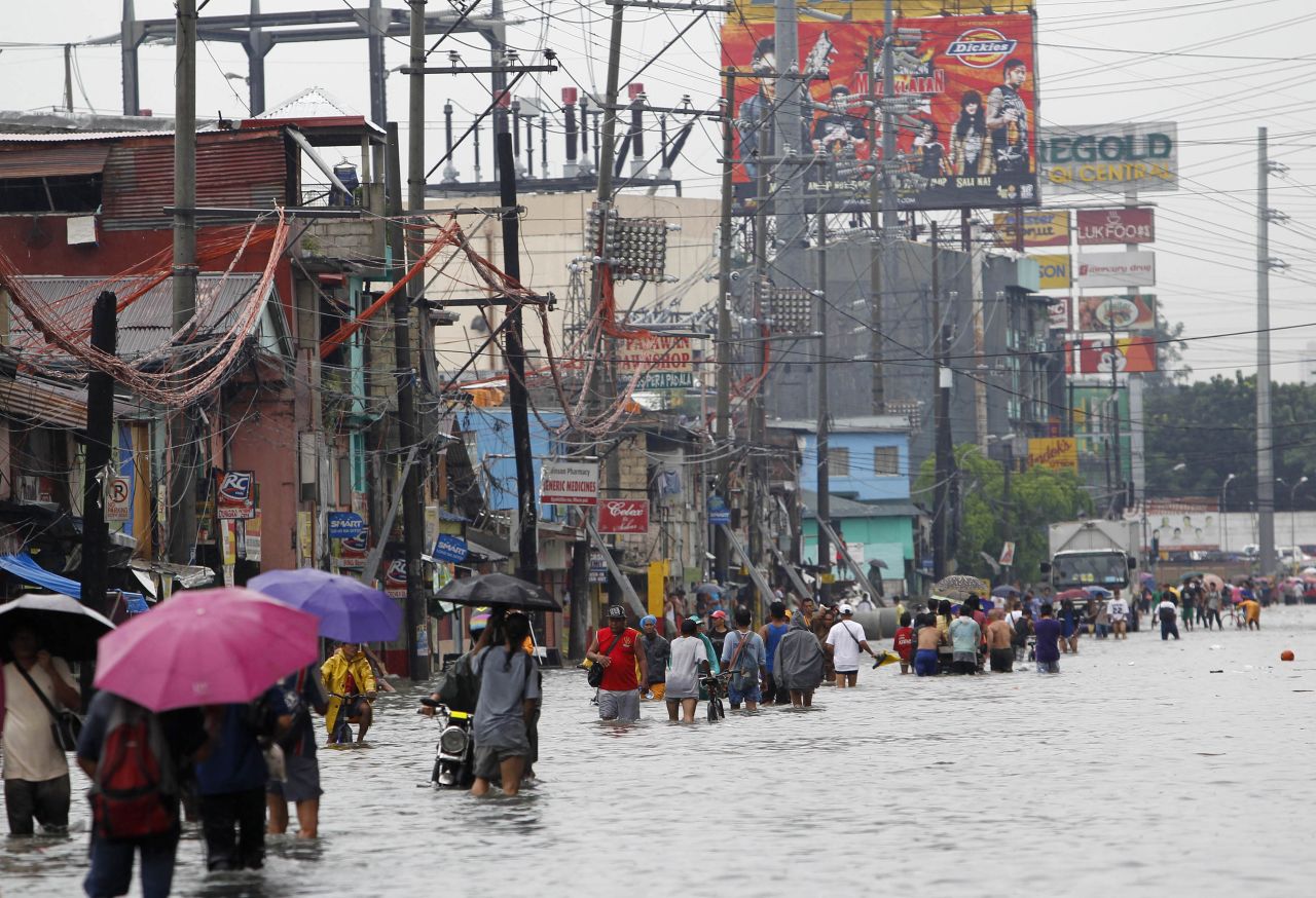 Commuters wade through a flooded street Saturday during a heavy downpour in Quezon City, in metro Manila.