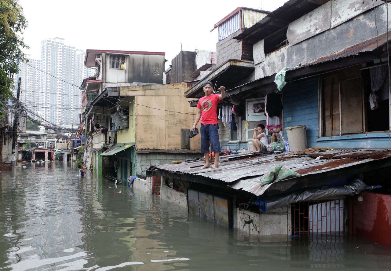 A man waits for a boat to transport him to higher ground on a flooded street after continuous overnight rain brought by Typhoon Sanba in San Juan, Philippines, on Saturday.
