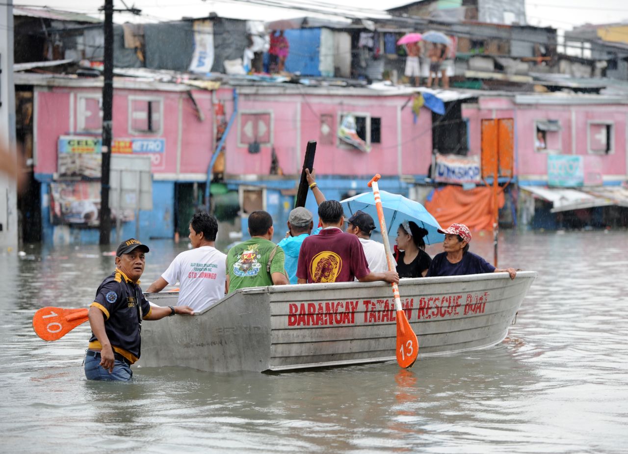 Residents ride on a boat near their flooded homes in Manila.