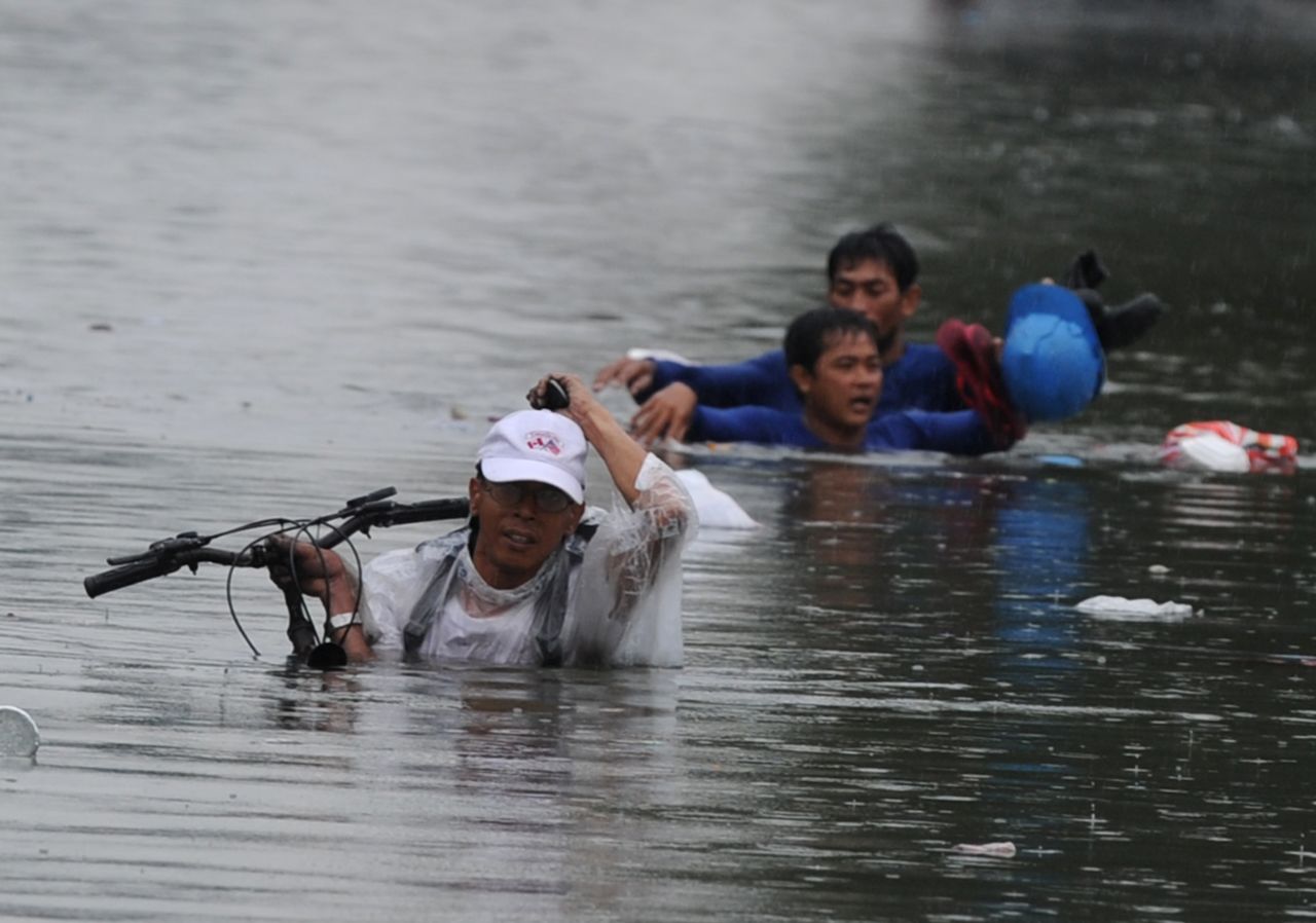 People try to hold onto their personal belongings as they wade along a flooded street in Manila.