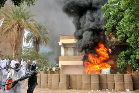 Smoke billows from the burning German Embassy in Khartoum, Sudan, as a policeman stands next to a man preparing to extinguish the fire caused by protesters the anti-Islam film. Around 5,000 protesters in the Sudanese capital stormed the embassies of Britain and Germany, which were torched and badly damaged.