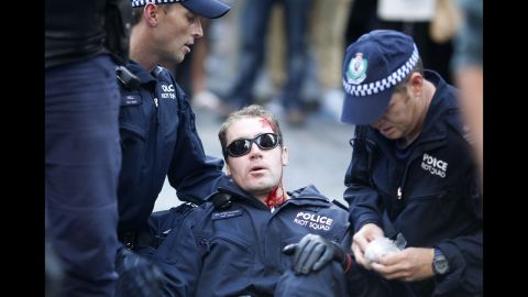  A policeman, injured by protesters, is assisted by colleagues in central Sydney on Saturday.
