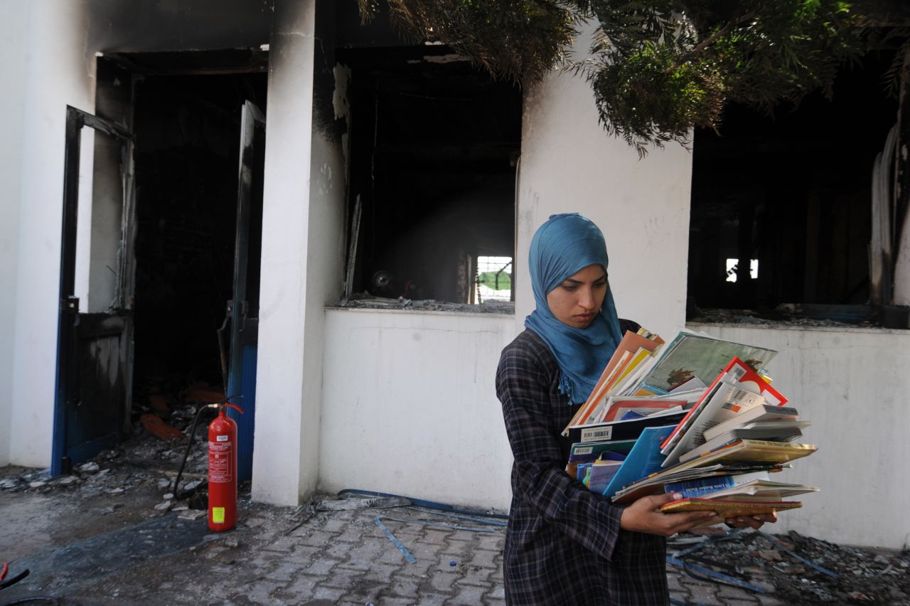 A  woman collects books from a classroom in the American school in Tunis on Saturday.