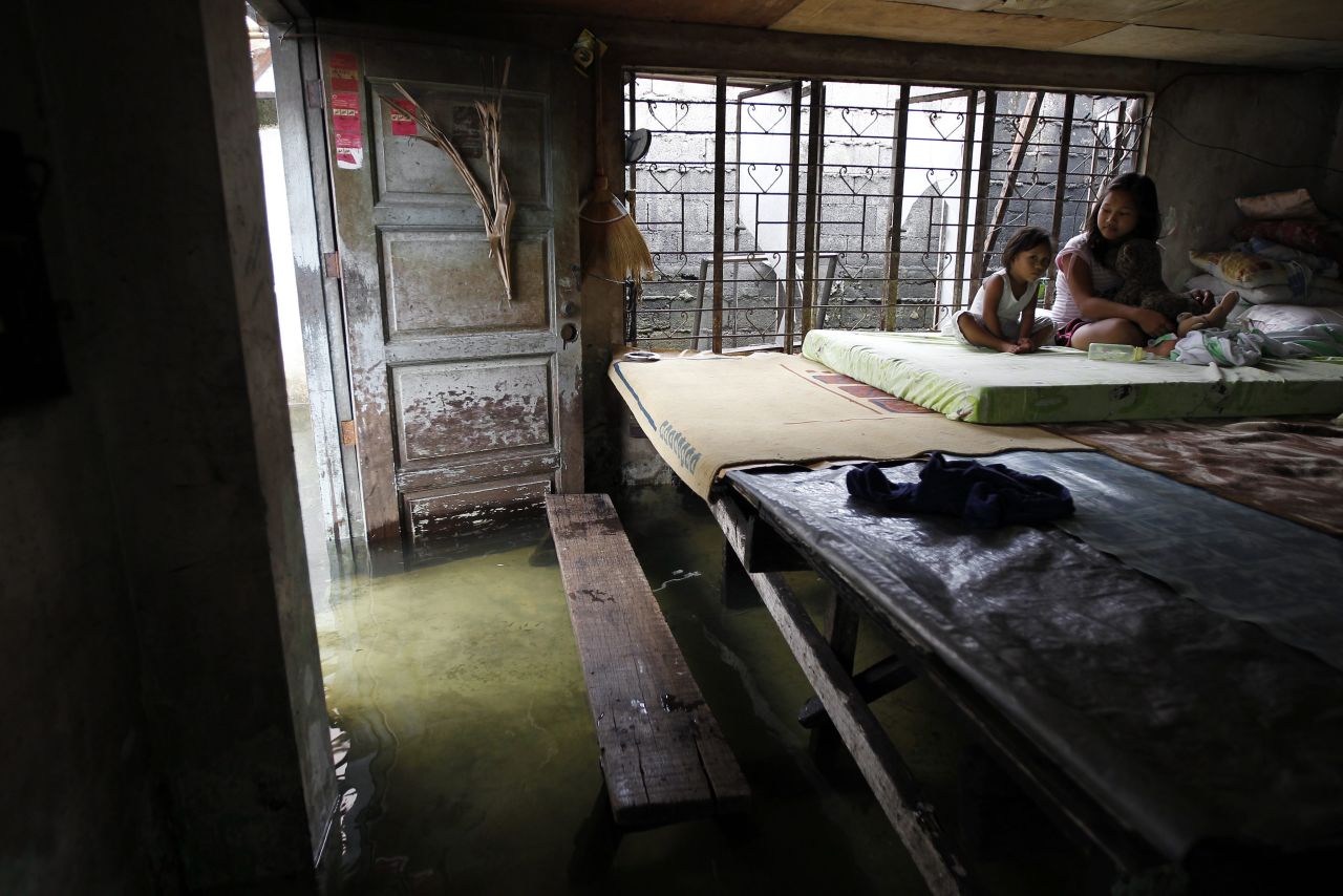 Filipino sisters Maria Fe, left, and Roxanne Jaime sit on an elevated bed inside their flooded home in Malabon City, Philippines, on Sunday.