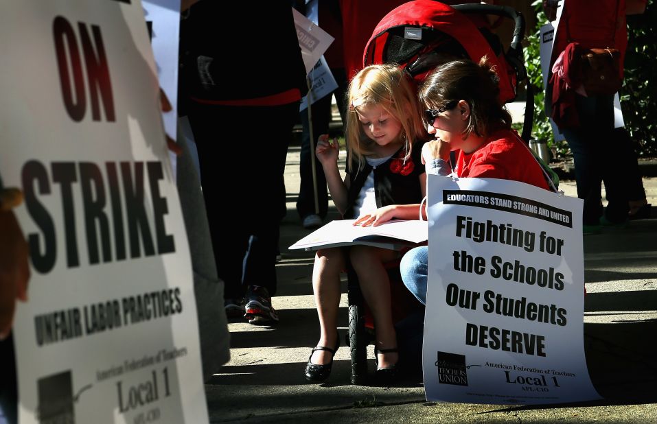 Teacher Jillian Connolly helps her daughter, Mary, study math while picketing outside of William H. Wells Community High School on Monday, September 10.