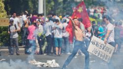 SHENZHEN, CHINA - SEPTEMBER 16: An nti-Japanese protester throws a gas cannister as they demonstrate over the disputed Diaoyu Islands, on September 16, 2012 in Shenzhen, China. Protests have taken place across China in a dispute that is becoming increasingly worrying for regional stability. (Photo by Lam Yik Fei/Getty Images) 
