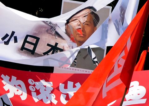 A shredded banner shows Japanese Prime Minister Yoshihiko Noda beside a picture of Mao Zedong in Beijing.