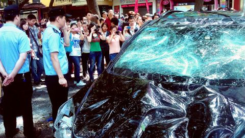 People take pictures of a Japanese car damaged in Xi'an on Saturday.