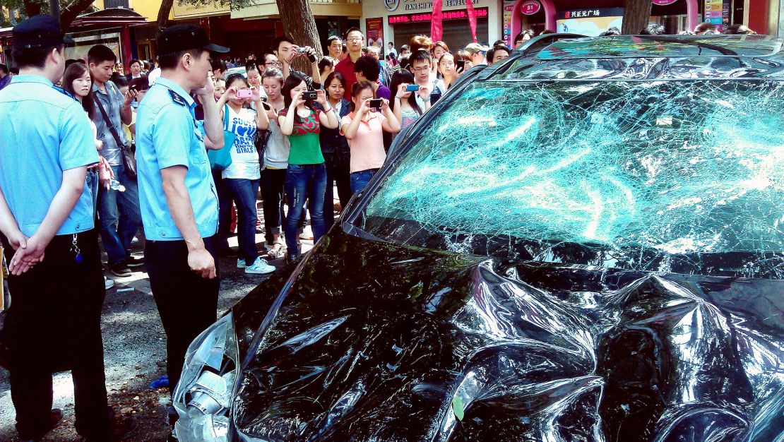 People take pictures of a Japanese car damaged during a protest against Japan's 'nationalizing' of the disputed Diaoyu Islands, also known as Senkaku Islands in Japan, in the Chinese city of Xi'an, on September 15, 2012. 