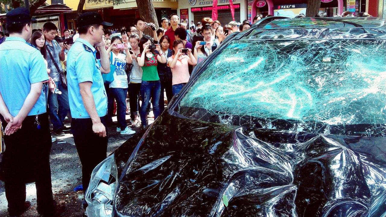 People take pictures of a Japanese car damaged during a protest against Japan's 'nationalizing' of the disputed Diaoyu Islands, also known as Senkaku Islands in Japan, in the Chinese city of Xi'an, on September 15, 2012. 