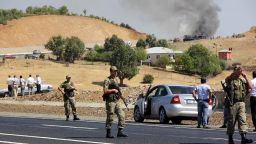 Turkish soldiers stand guard as smokes rises from a bus attacked by members of the PKK on September 18, 2012, in Bingol.