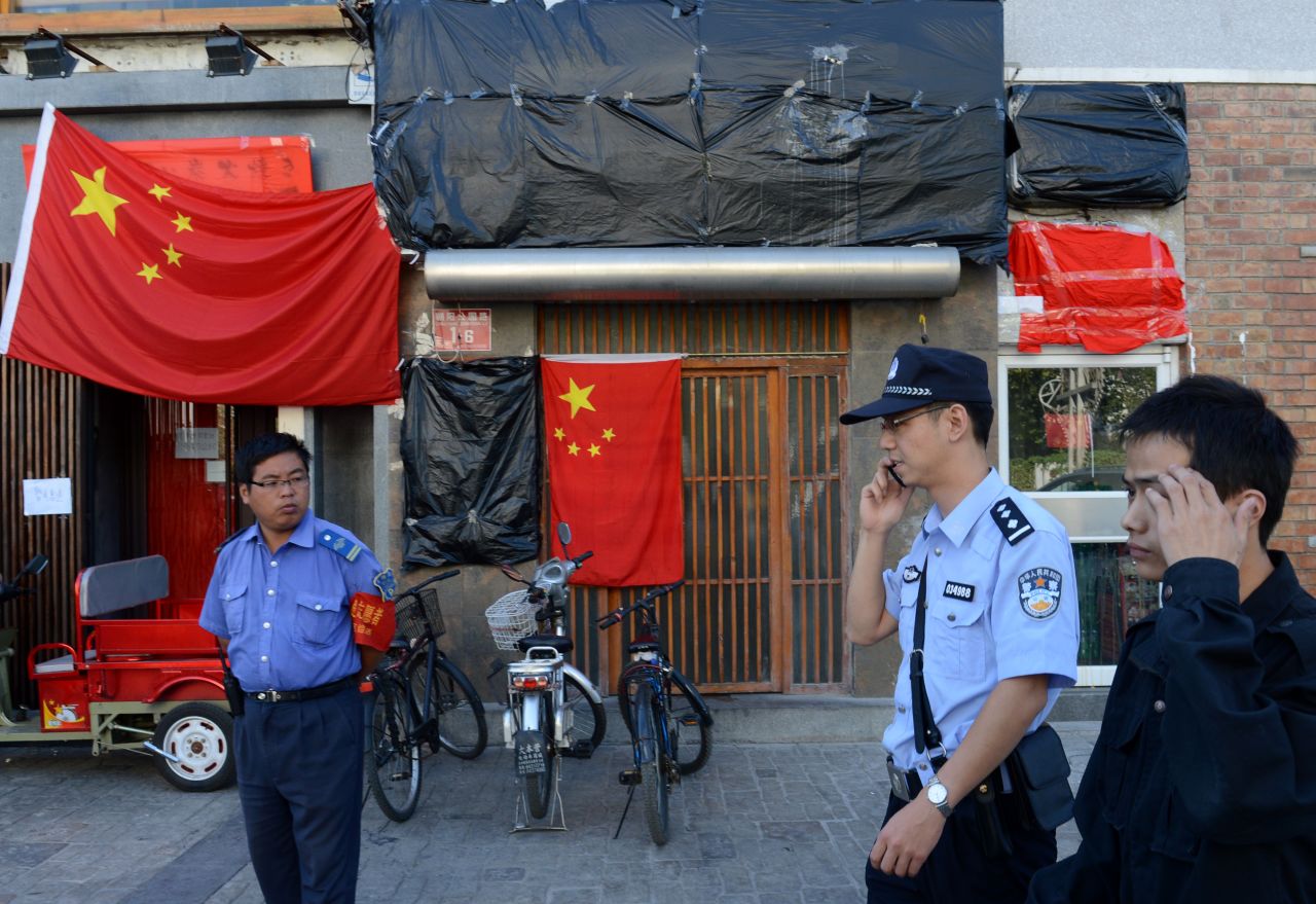 Police walk past a closed Japanese restaurant covered with Chinese national flags as anti-Japanese protests continued outside the Japanese Embassy in Beijing on September 17.