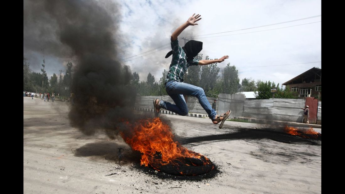 A Kashmiri Muslim boy jumps over a burning tire set up as a roadblock during Tuesday's demonstration Srinagar.