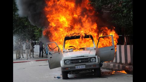 Firefighters attempt to extinguish the flames in an Indian police vehicle  as protesters clash with police during a protest and in Srinagar, Kashmir, on Tuesday.