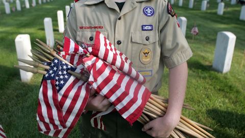  A Boy Scout holds flags that he and other Scouts are going to place on graves at a cemetery in Louisville, Kentucky. 