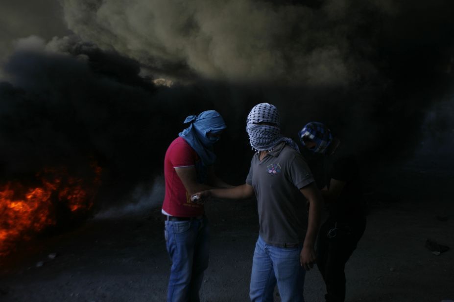 Masked Palestinians are seen during clashes with Israeli security forces in Shuafat refugee camp, Jerusalem, on Tuesday, September 18.