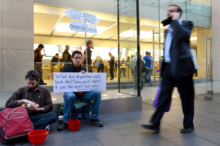 Francis Le holds up a placard in his mock food queue outside Apple's flagship store in Sydney on Thursday in a form of protest against people waiting to buy the iPhone 5. Le is seeking to highlight what he calls the madness of endless consumption and to contrast it with desperate, hungry people around the world.