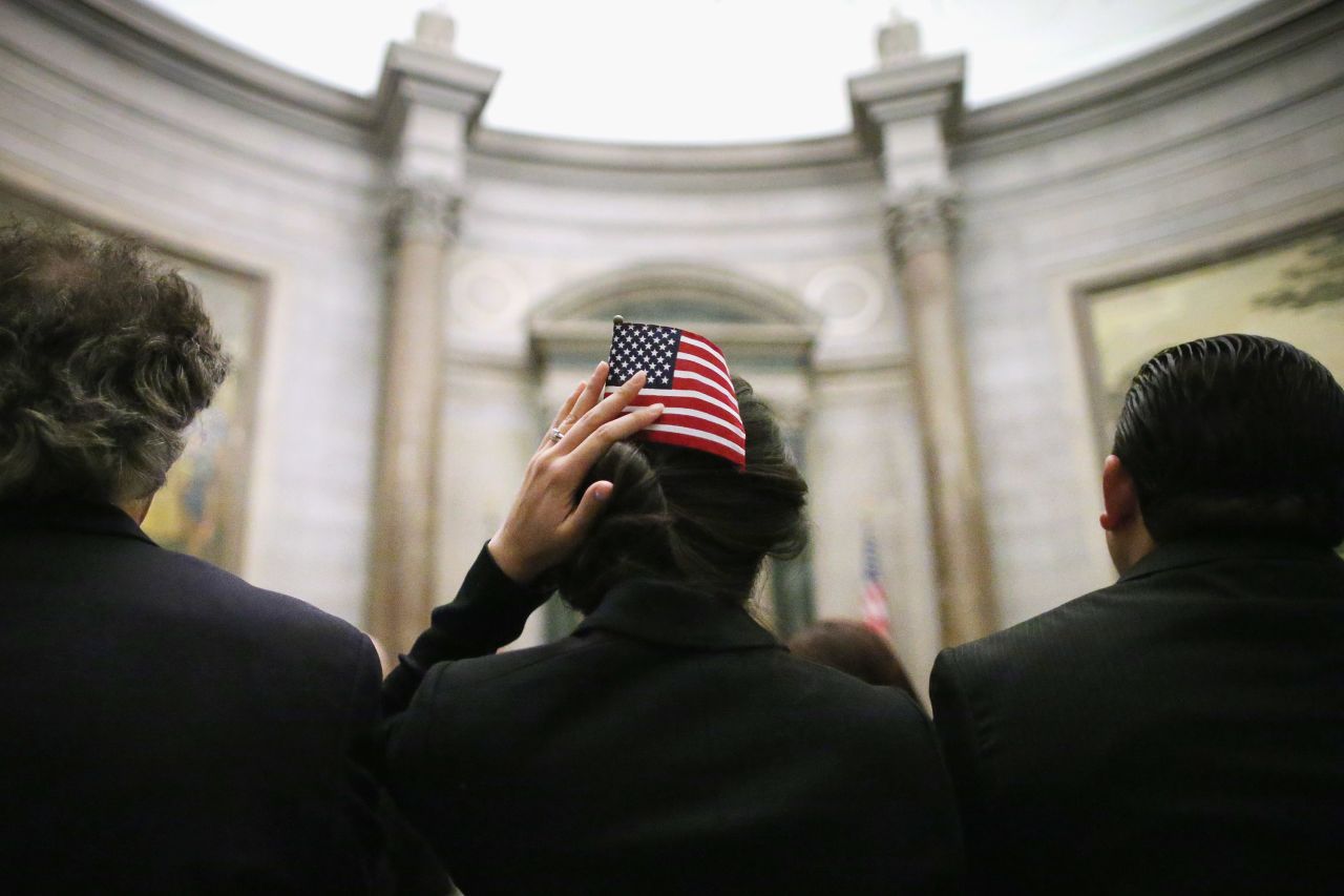 A native of Lebanon, Mirna Mumm uses a U.S. flag to hold her hair in place after becoming one of 215 new citizens during a ceremony at the National Archives on Monday in Washington. The ceremony was held on the 225th anniversary of the signing of the U.S. Constitution.