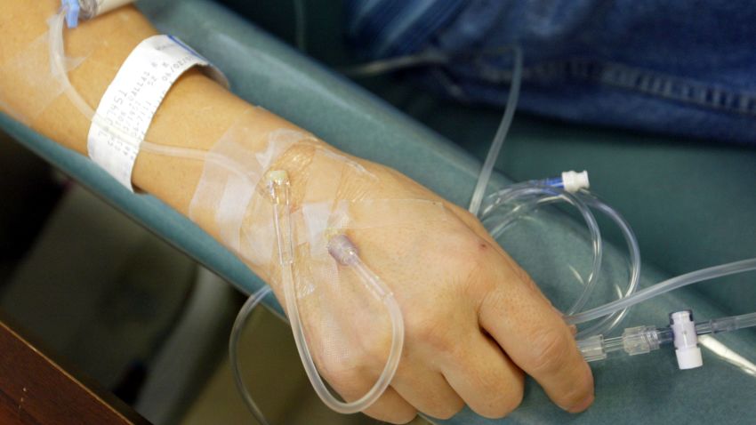 A cancer patient holds the IV tubes during chemotherapy.
