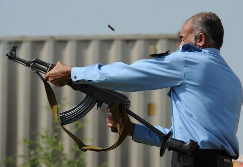 A Pakistani police officer fires an automatic weapon toward demonstrators during a protest Friday in Islamabad.