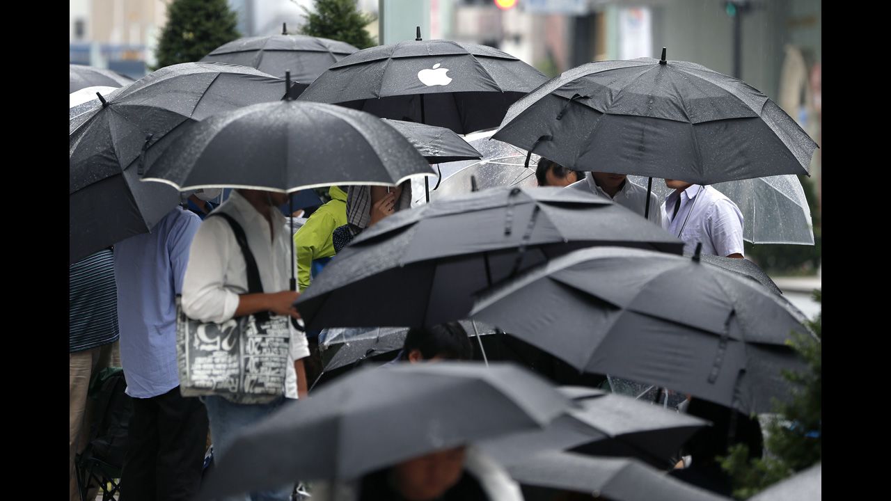 Customers hold umbrellas as they wait in line in Tokyo.