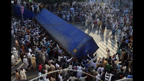 Pakistani Muslim demonstrators topple a freight container that was placed by police to block a street during a protest on Friday.