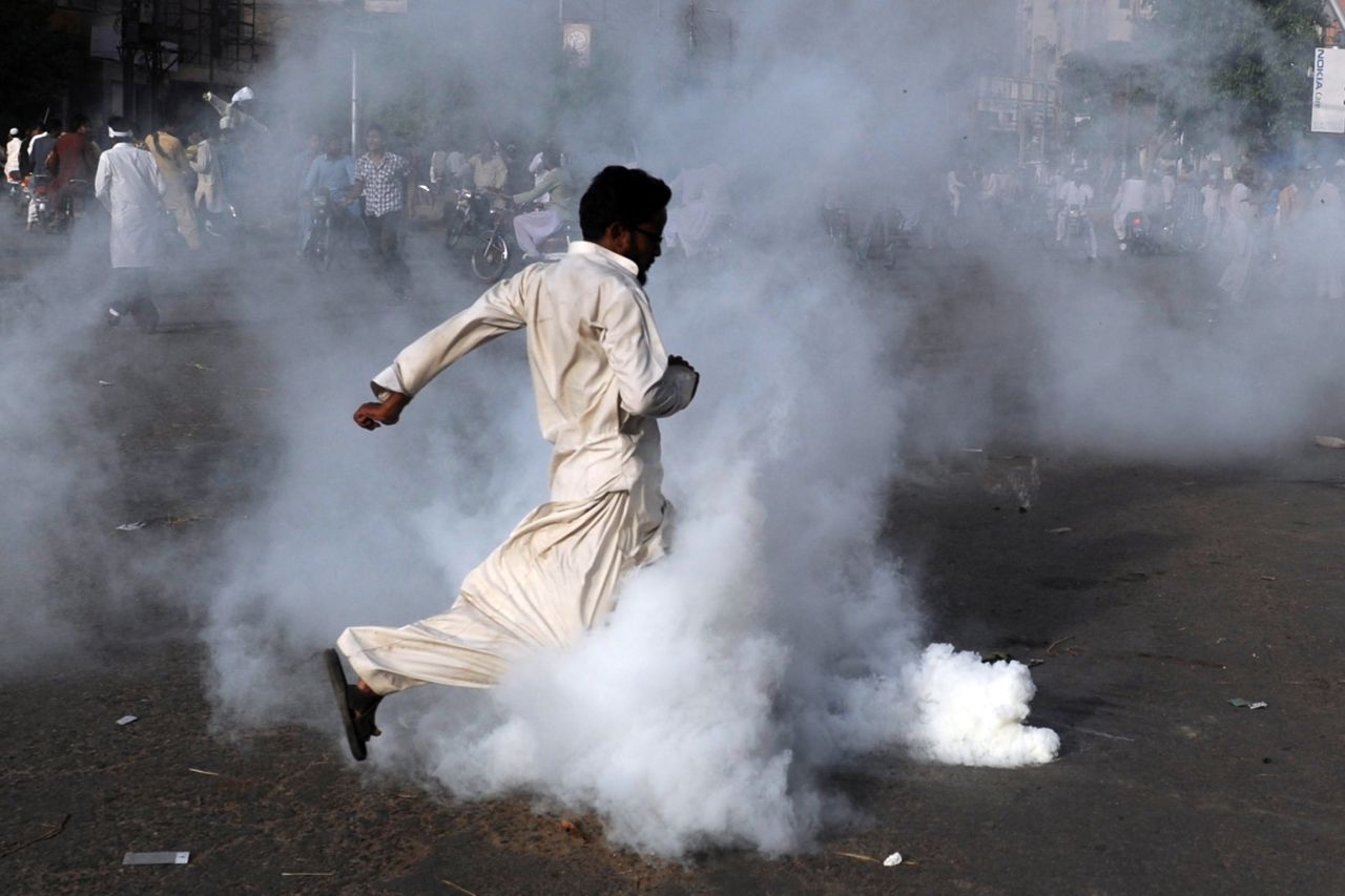 A demonstrator kicks a tear gas shell in Karachi, Pakistan, on Friday.