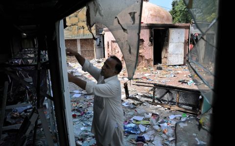 A worker inspects his damaged shop following violent protests in Peshawar, Pakistan, on Saturday.