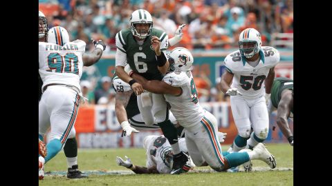 Jared Odrick of the Miami Dolphins hits Mark Sanchez of the New York Jets as he gets the ball away.