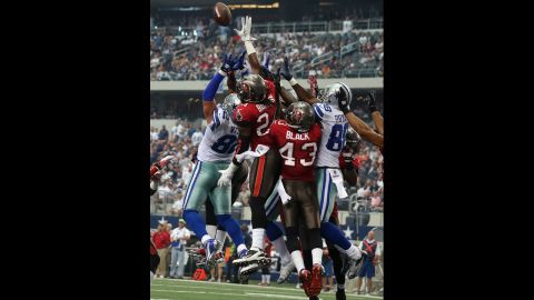 Cowboys and Buccaneers players jump for the ball in the endzone.