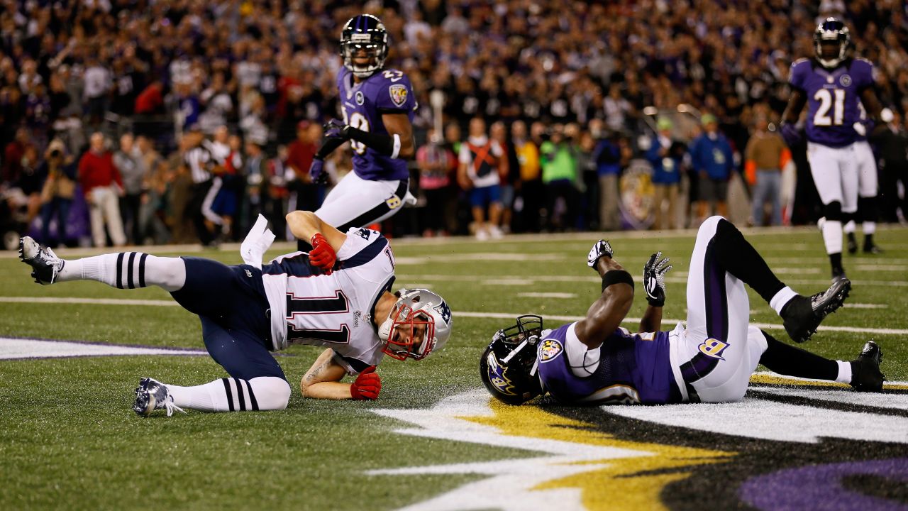 New England's Julian Edelman falls to the turf after taking a hit from Baltimore's Ed Reed.