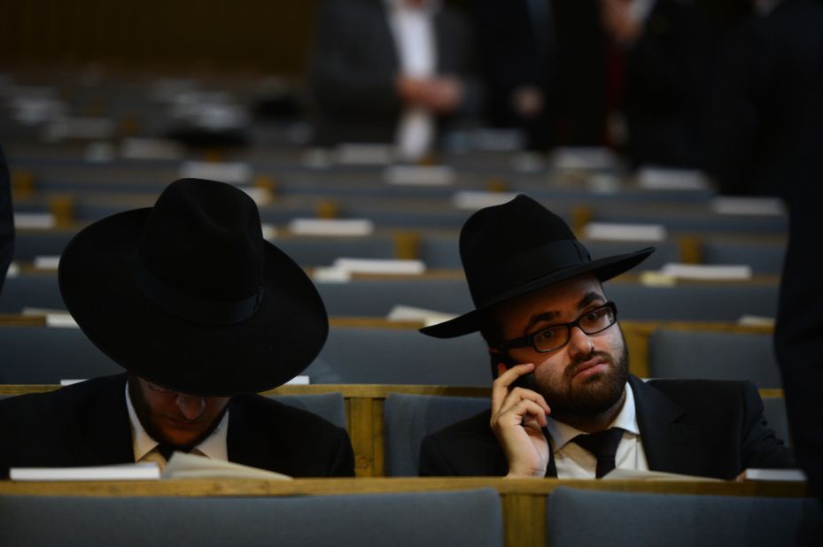 A man uses his phone before a ceremony to ordain four rabbis in a German synagogue. 