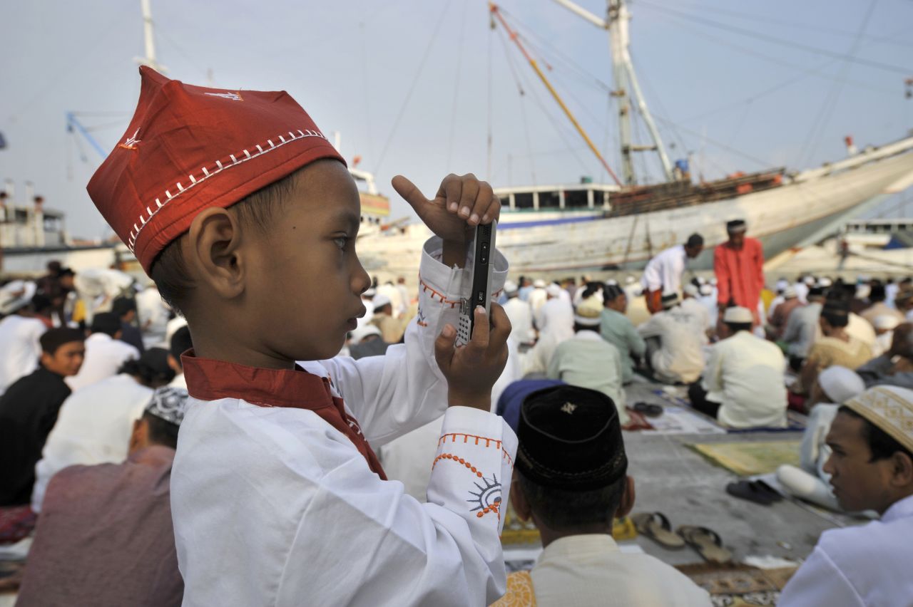 A young Indonesian boy takes a photo with a mobile phone following prayers at the old Jakarta port of Sunda Kelapa where he was celebrating the three-day Eid al-Fitr festival. 