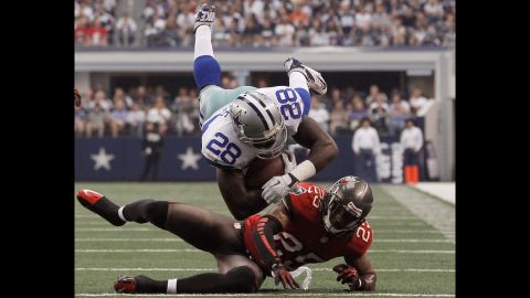 Felix Jones of the Dallas Cowboys is tripped up by D.J. Ware of the Tampa Bay Buccaneers on Sunday in Arlington, Texas.