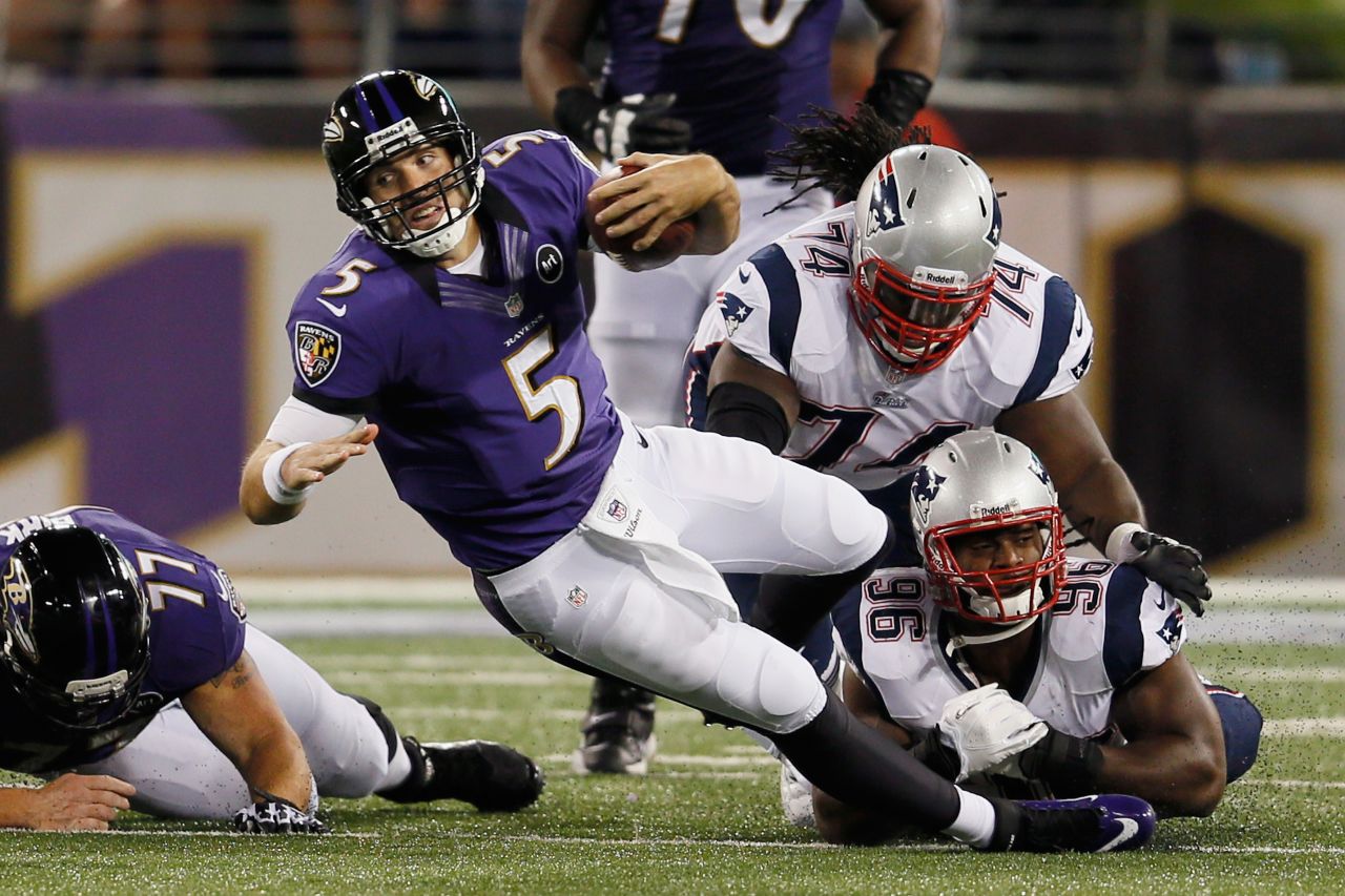 Quarterback Joe Flacco of the Ravens is brought down by No. 74 Kyle Love and No. 96 Jermaine Cunningham of the Patriots after scrambling for a first down on Sunday.