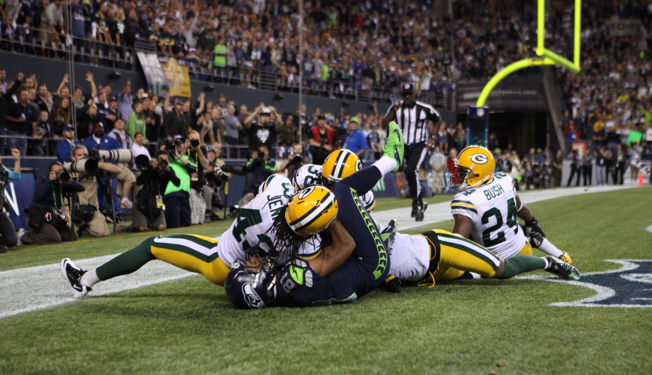 The group falls to the ground in the end zone. Packers defensive back M.D. Jennings appeared to intercept the pass and had both hands wrapped around the ball with the ball pulled into his chest. 