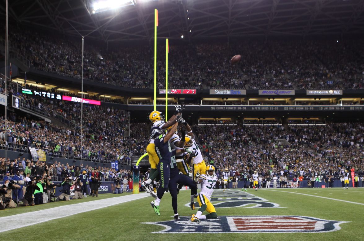 Seahawks wide receiver Golden Tate, in navy blue, jumps for the ball, surrounded by Green Bay players. Before he made the catch in the end zone, Tate shoved Packers defender Sam Shields in the back, which would typically draw an offensive pass interference penalty.