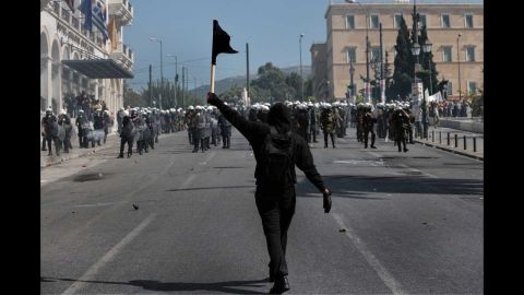A demonstrator waves a black flag in front of riot police in Athens on Wednesday.
