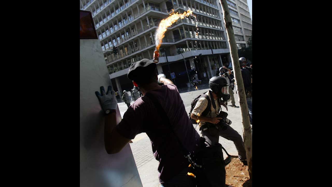 A demostrator throws a Molotov cocktail toward riot police near Syntagma Square in Athens on Wednesday.