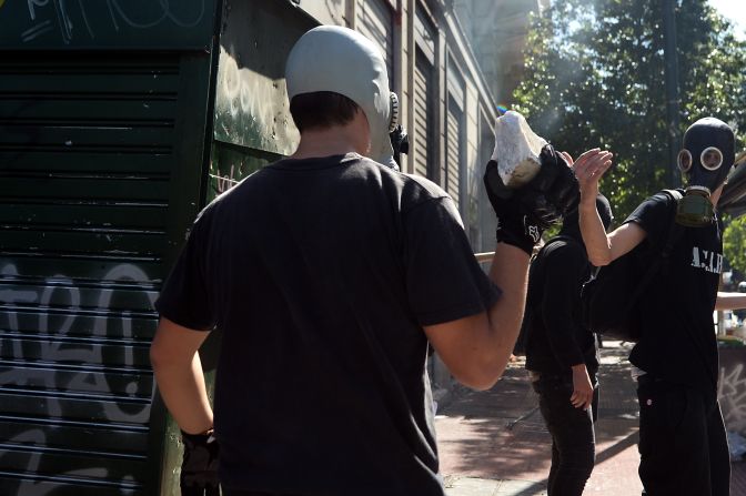 Demonstrators carry stones and wear masks during clashes Wednesday.